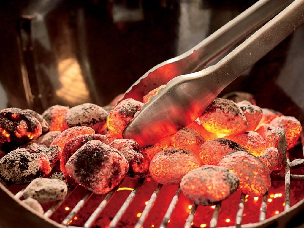 Glowing charcoal being handled with tongs
